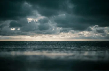 A captivating view of the ocean with dramatic dark clouds above, presenting a moody and dramatic seascape.